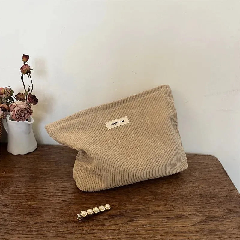 Bag held in hand demonstrating clutch-style design and closure