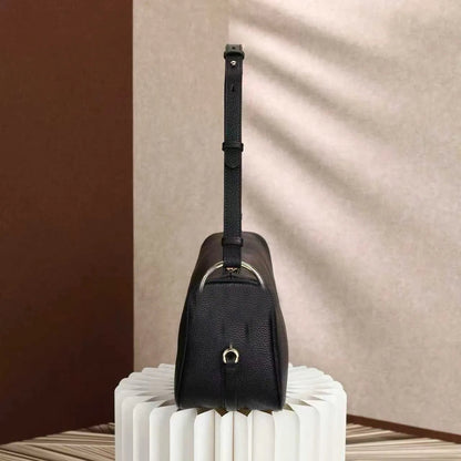 Side view of satchel bag displaying interior compartments and closure