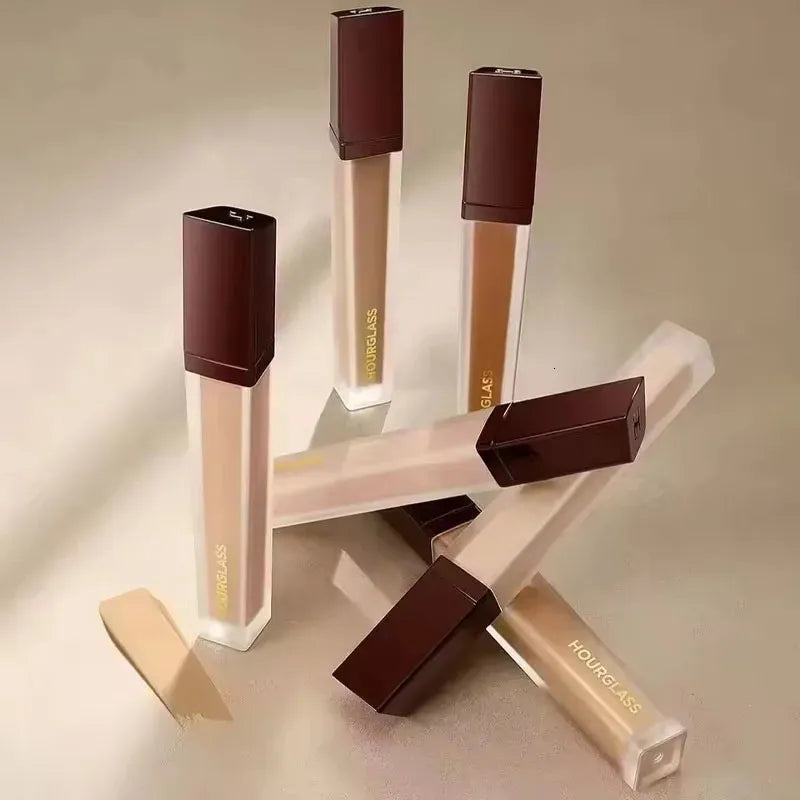 Liquid concealer bottle with applicator on a neutral background