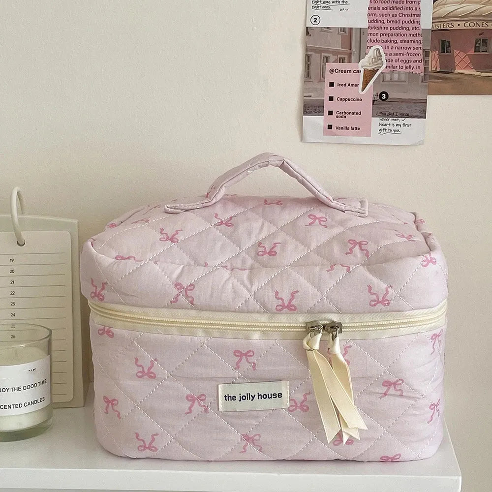 Front view of pink quilted cosmetic bag with bowknot decoration