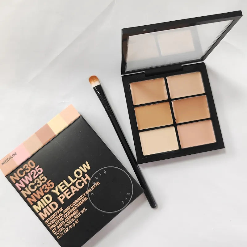 Makeup brush applying cream concealer from palette to hand for swatch demonstration