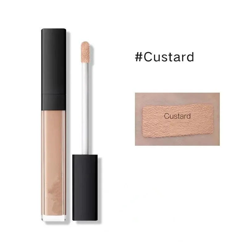 Concealer container with applicator shown next to makeup brush