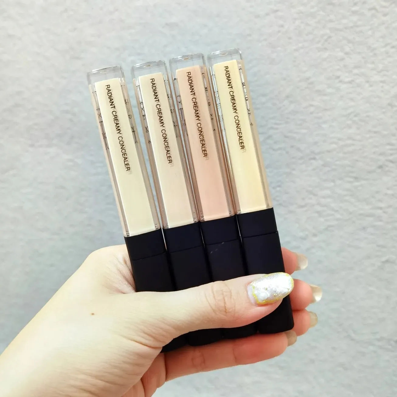 Four different shade options of creamy liquid concealer displayed together