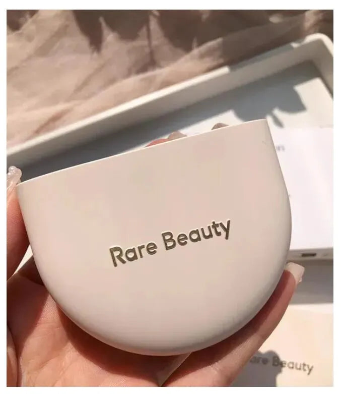 Two identical pressed powder compacts with mirrors open on a flat surface