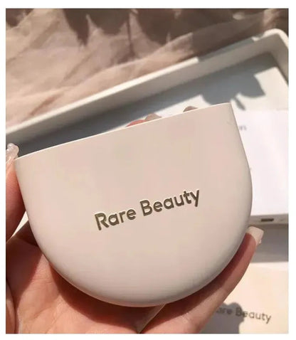 Two identical pressed powder compacts with mirrors open on a flat surface