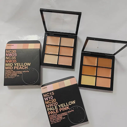 Makeup brush applying cream concealer from palette to hand for swatch demonstration