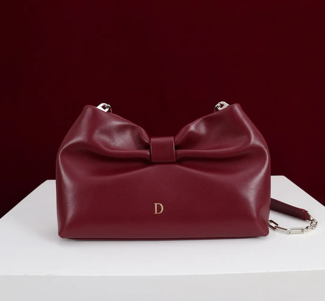 Front view of women's clutch bag with bow design in dark grey color