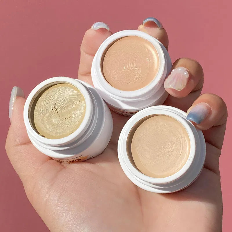 Liquid concealer tube with applicator shown on a neutral background