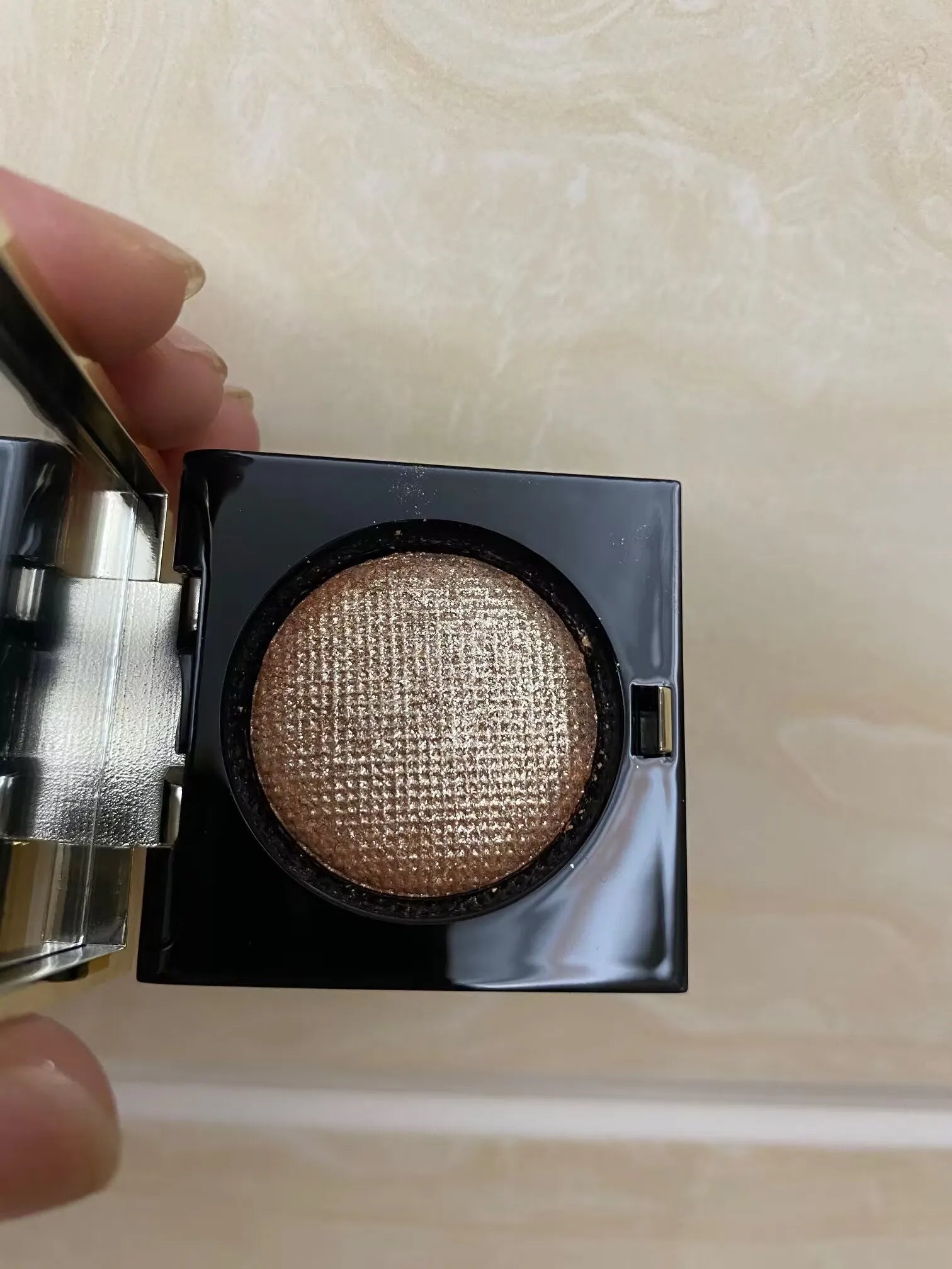 Brown eye shadow compact with sparkle finish on a neutral background
