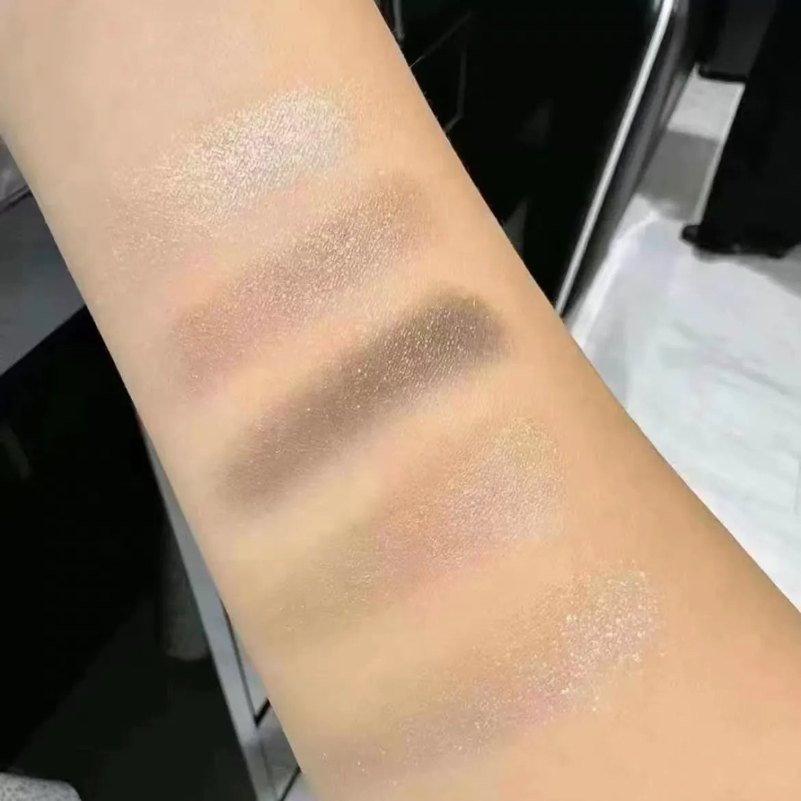 Eyeshadow palette in use with brush application on a hand swatch