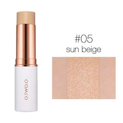 Hand holding a concealer stick with swatches of all six shades visible