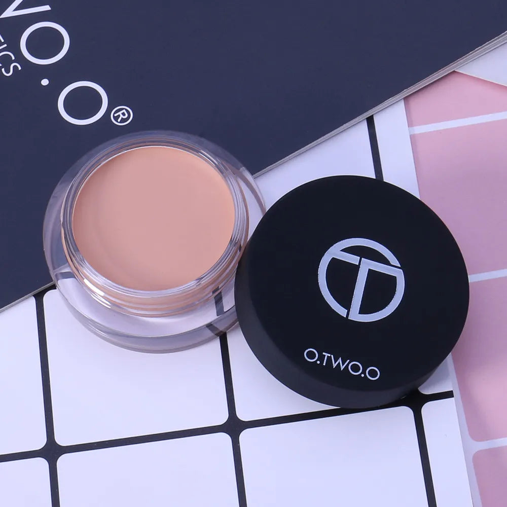 Four small containers of cream concealer arranged in a row