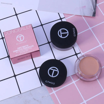 Hand holding a compact with multiple concealer shades visible